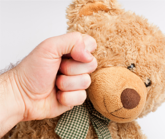 Child's fist hitting teddy bear
